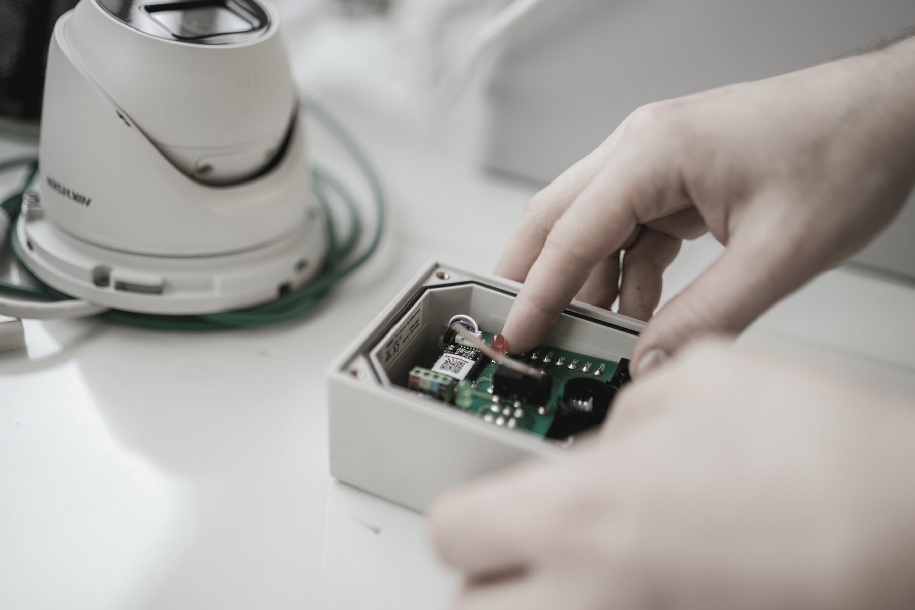 Hand setzt eine bestückte Platine in ein Kameragehäuse ein