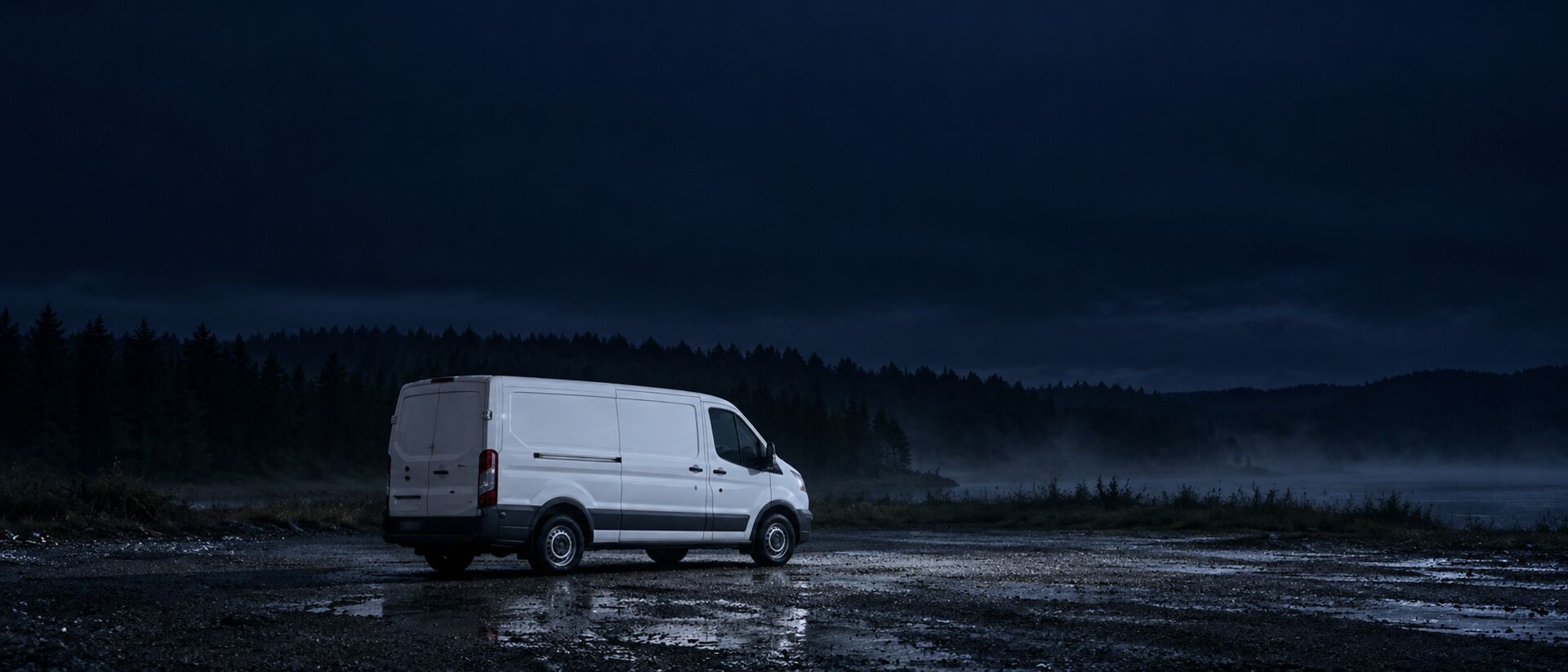 Einzeln abgestellter Transporter auf unbeleuchtetem Schotterplatz bei Nacht