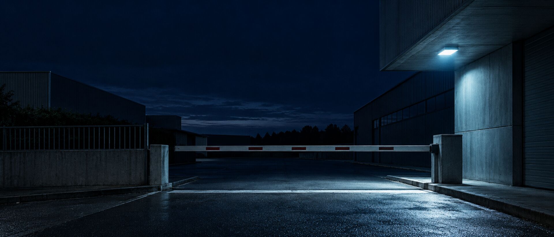 Geschlossene Werkszufahrt bei Nacht mit heruntergelassener Schranke